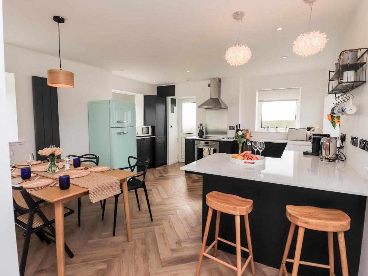 a kitchen and living room with a table and chairs at Park Cottage in Carinish
