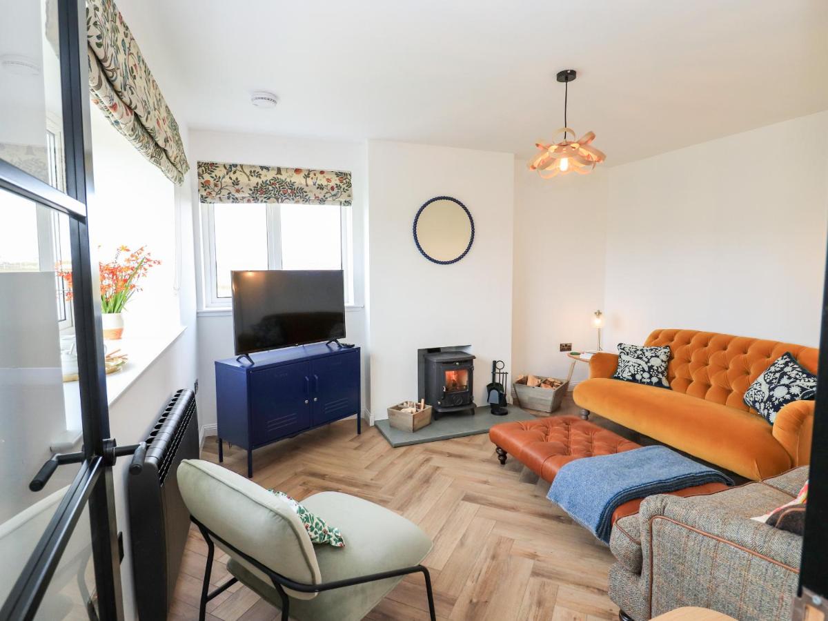 a living room with a couch and a tv at Park Cottage in Carinish