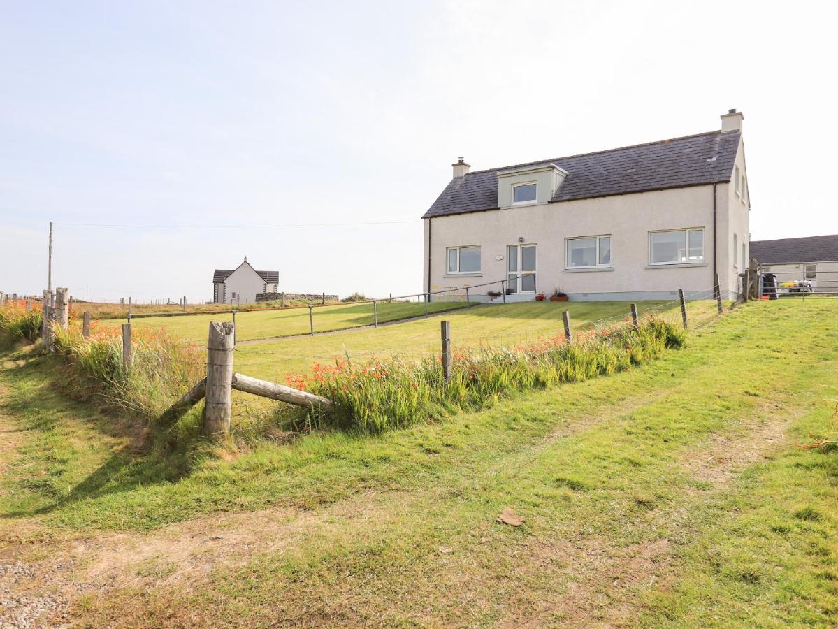 a house in a field next to a fence at Park Cottage in Carinish