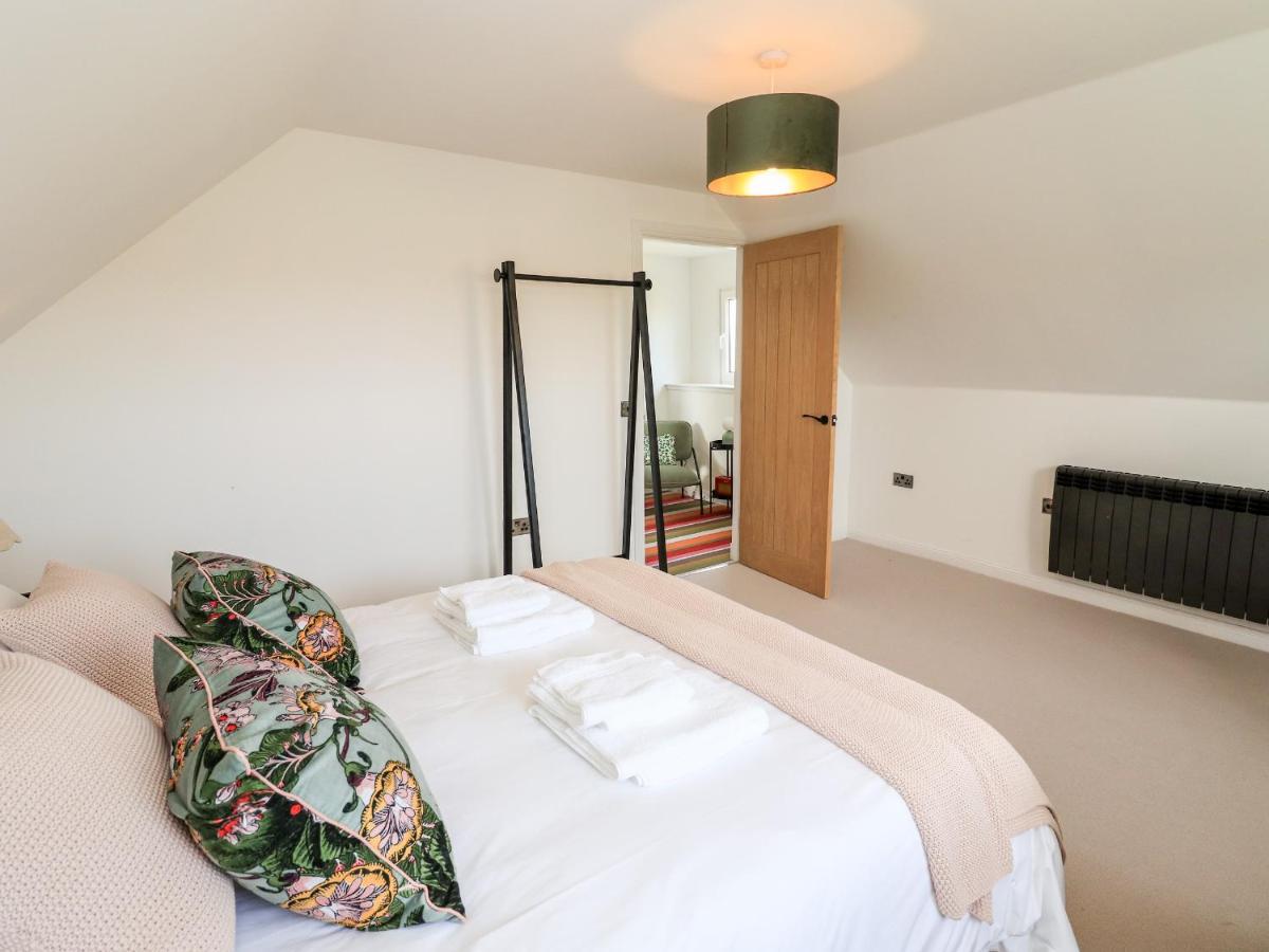 a bedroom with a white bed with a pillow on it at Park Cottage in Carinish