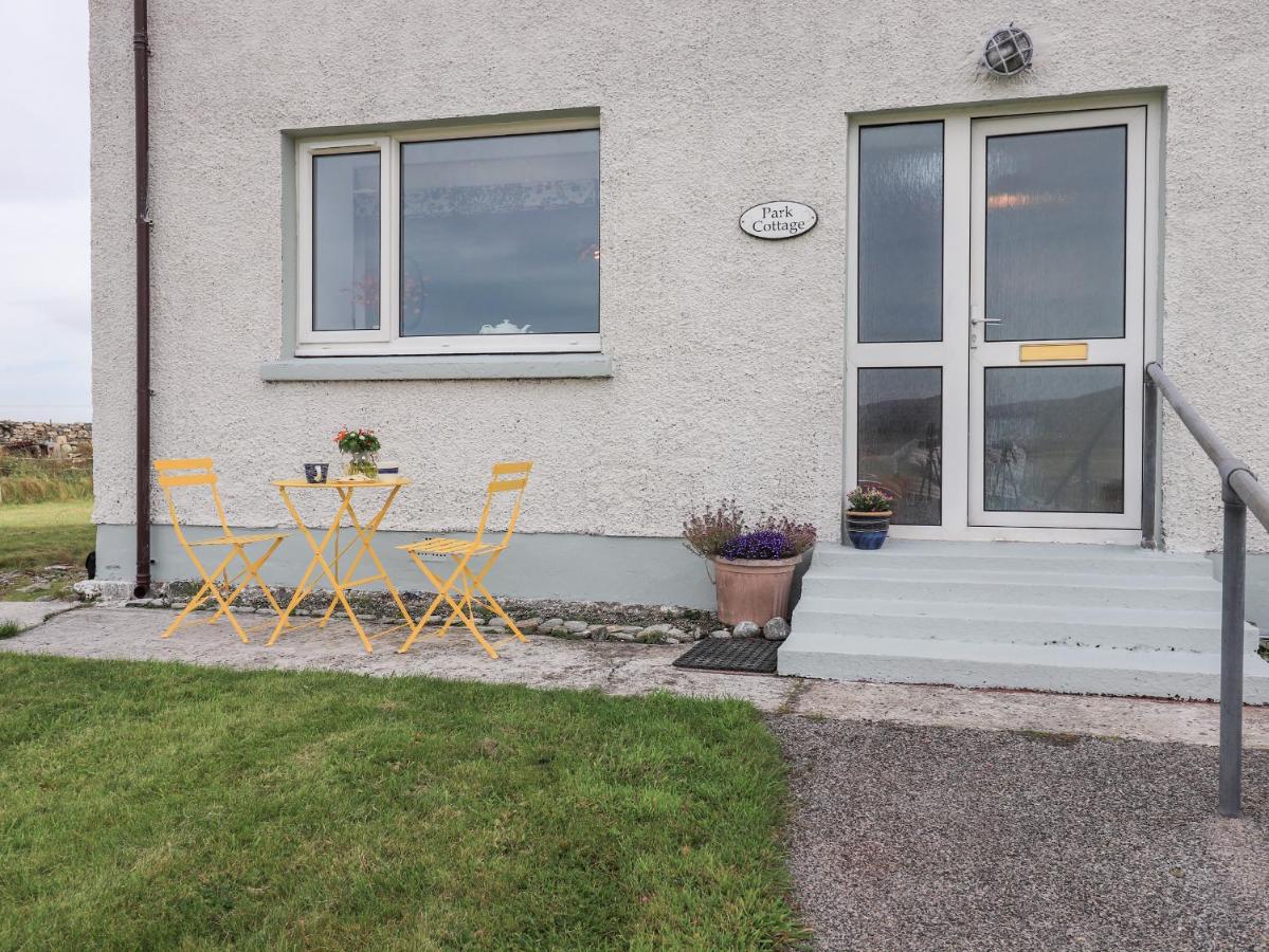 a table and chairs in front of a house at Park Cottage in Carinish